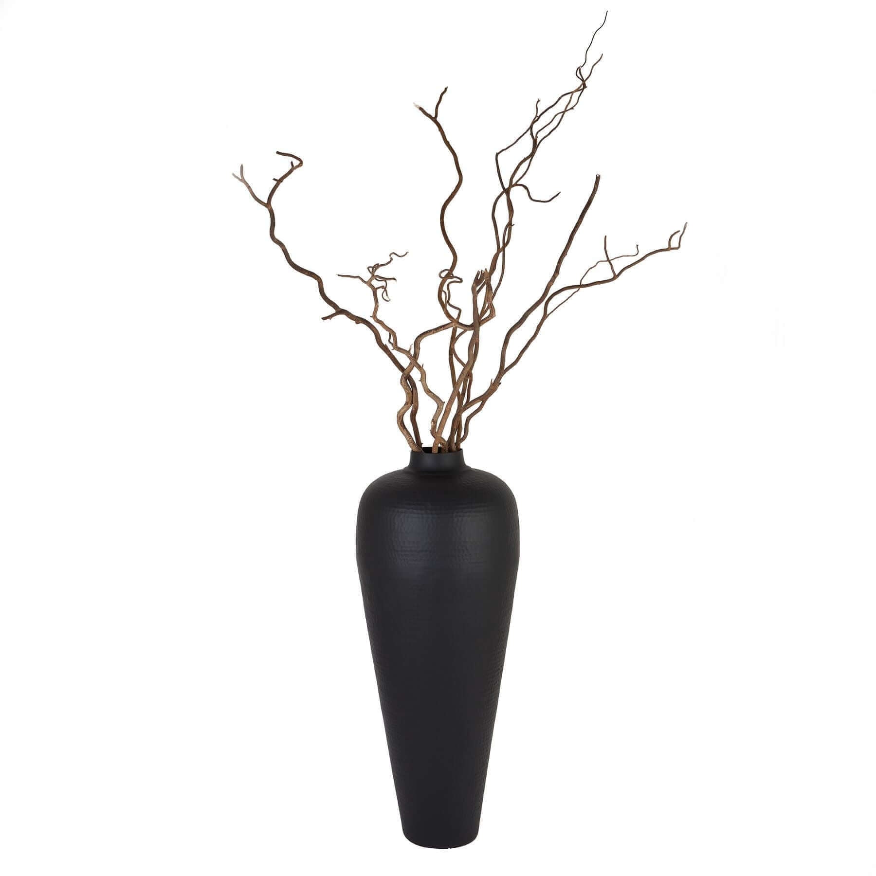 Medium Hammered Vase | Description Discover the sleek style of the Medium Hammered Vase in matt black, crafted by hand from durable steel. Perfect for displaying floor standing with twisted hazel branches, this contemporary vase brings a touch of elegance