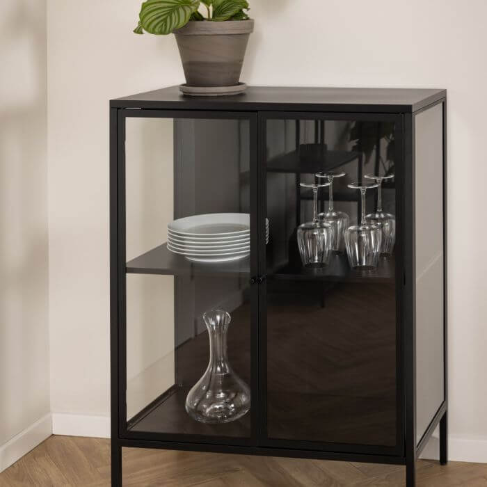 Newcastle Low Display Cabinet in matt black steel with clear tempered glass doors, featuring elegant glassware and plates displayed inside